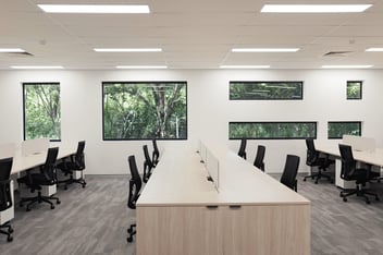 wooden workstation with black chairs and white wall with windows