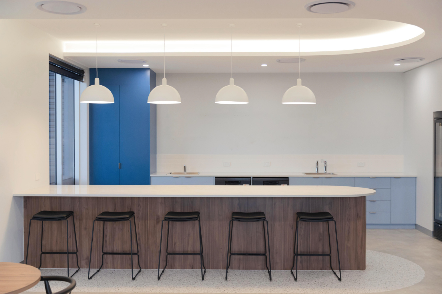 kitchen space with blue cabinetry, white pendant lights and black stools