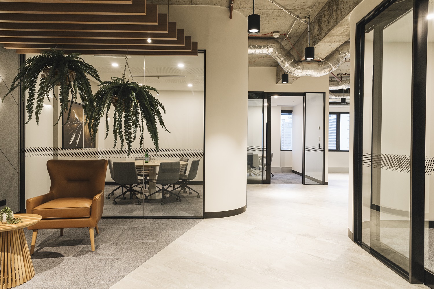 curved wall upon entry into suites with hanging planters and tan coloured leather chairs