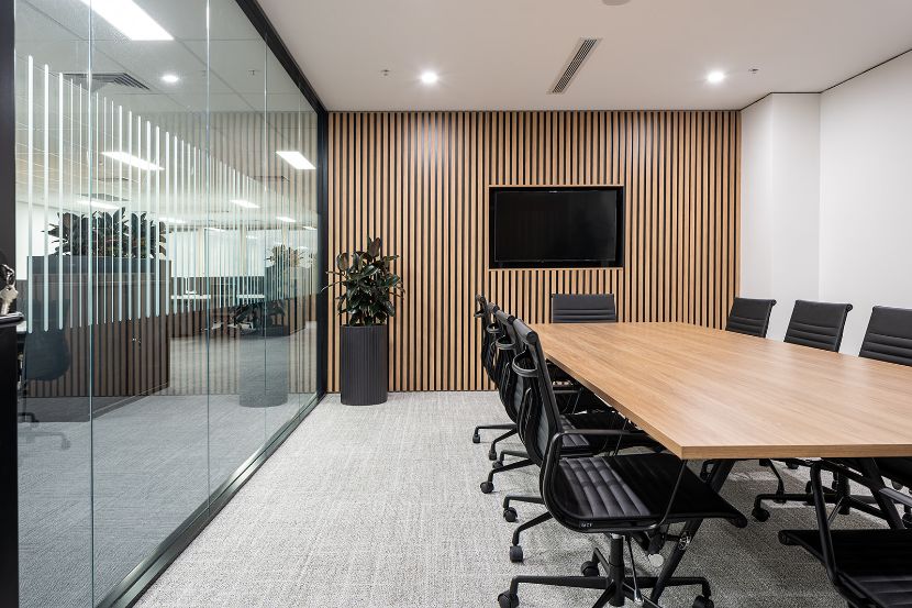 timber boardroom table and slatted feature wall with black chairs