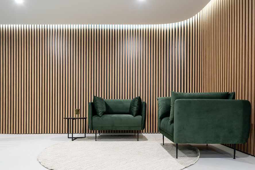 timber cladded wall with green armchairs