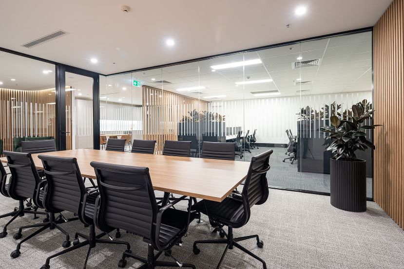 boardroom wooden table with high black office chairs, a black planter, looking out the glass walls