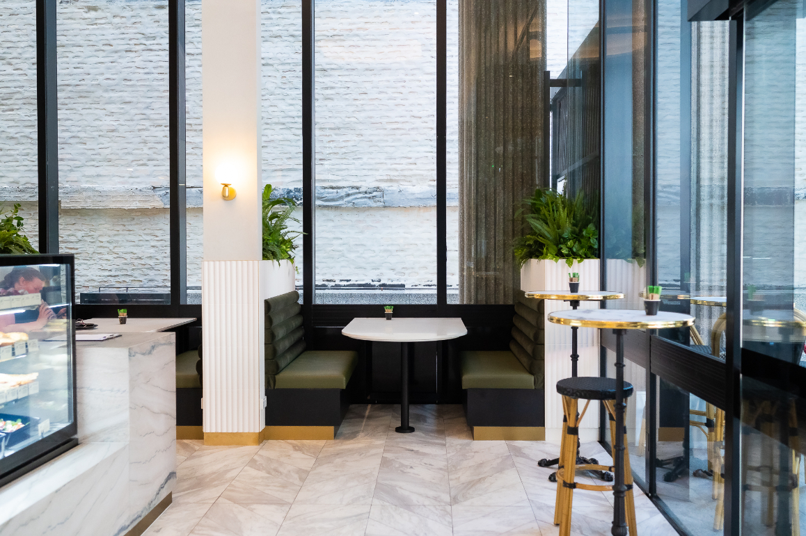 inside lait noir cafe showing marble tiles and booth seating with planters