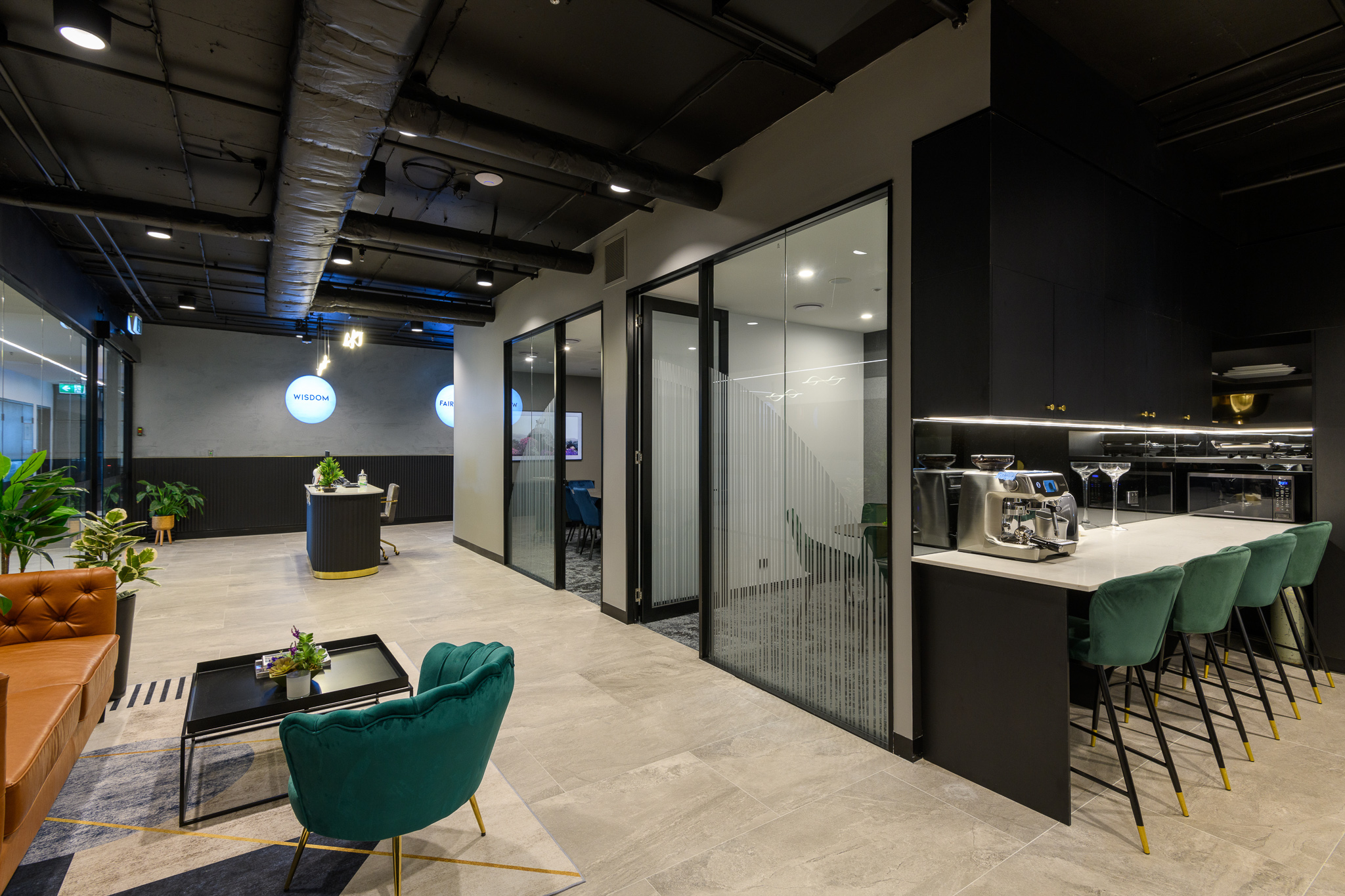 a large front entry to solomons capital office featuring 2 offices and green chairs and grey flooring with a black exposed ceiling